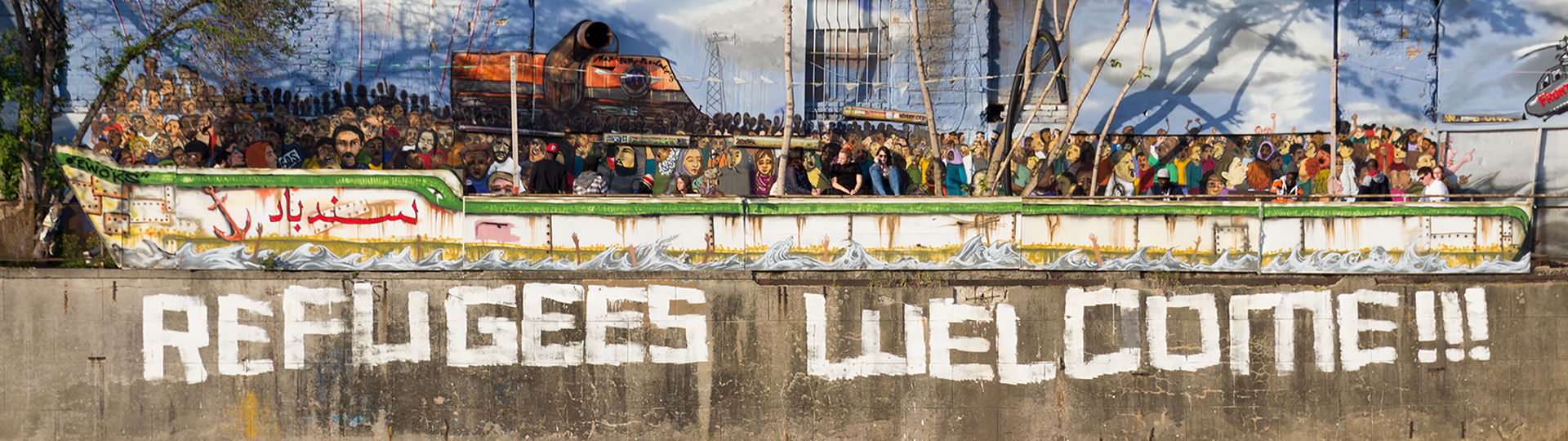 Foto einer Ufer-Mauer mit der Aufschrift "Refugees welcome".