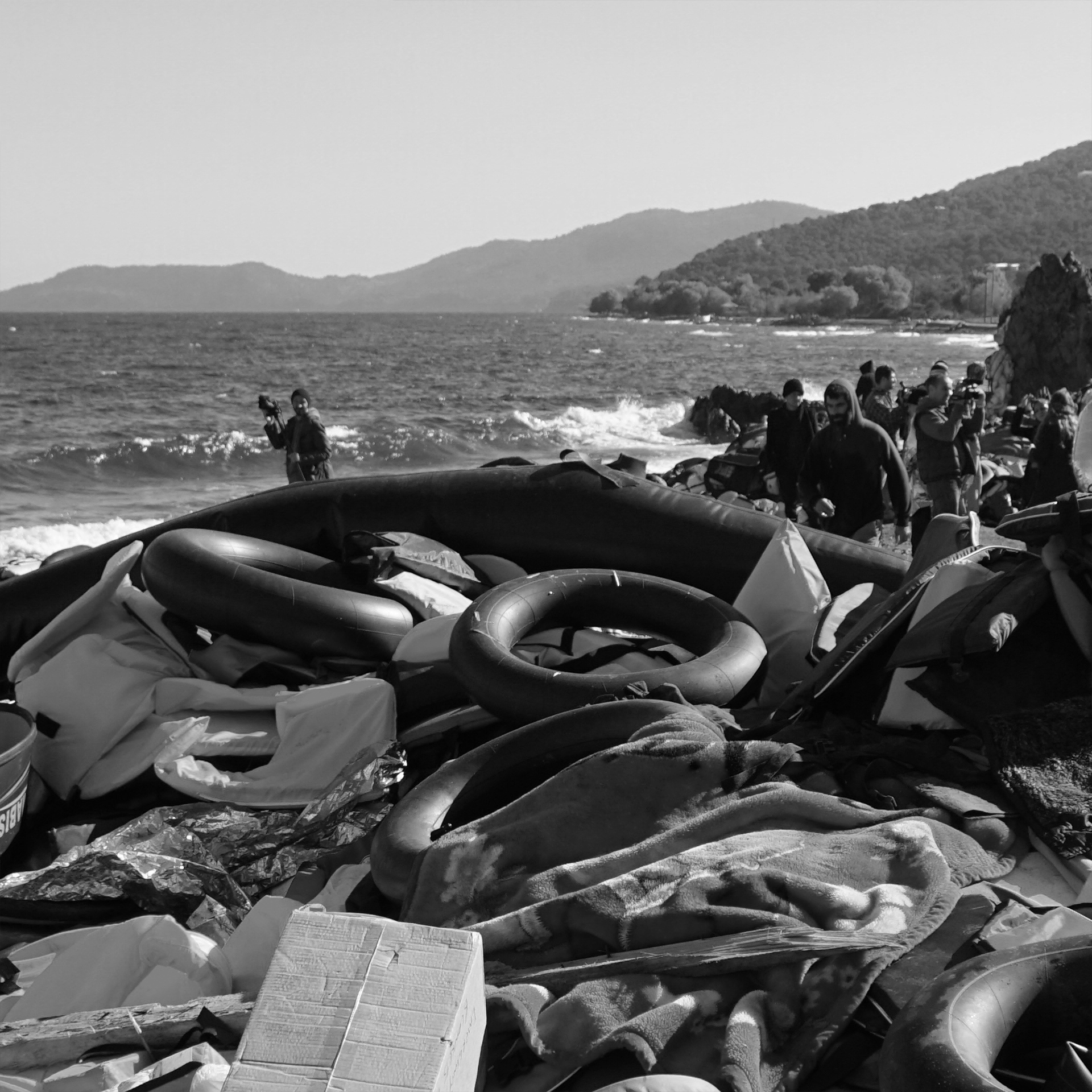 Schwarz-Weiß-Fotografie eines Strandes mit zahlreichen Rettungswesten und -reifen