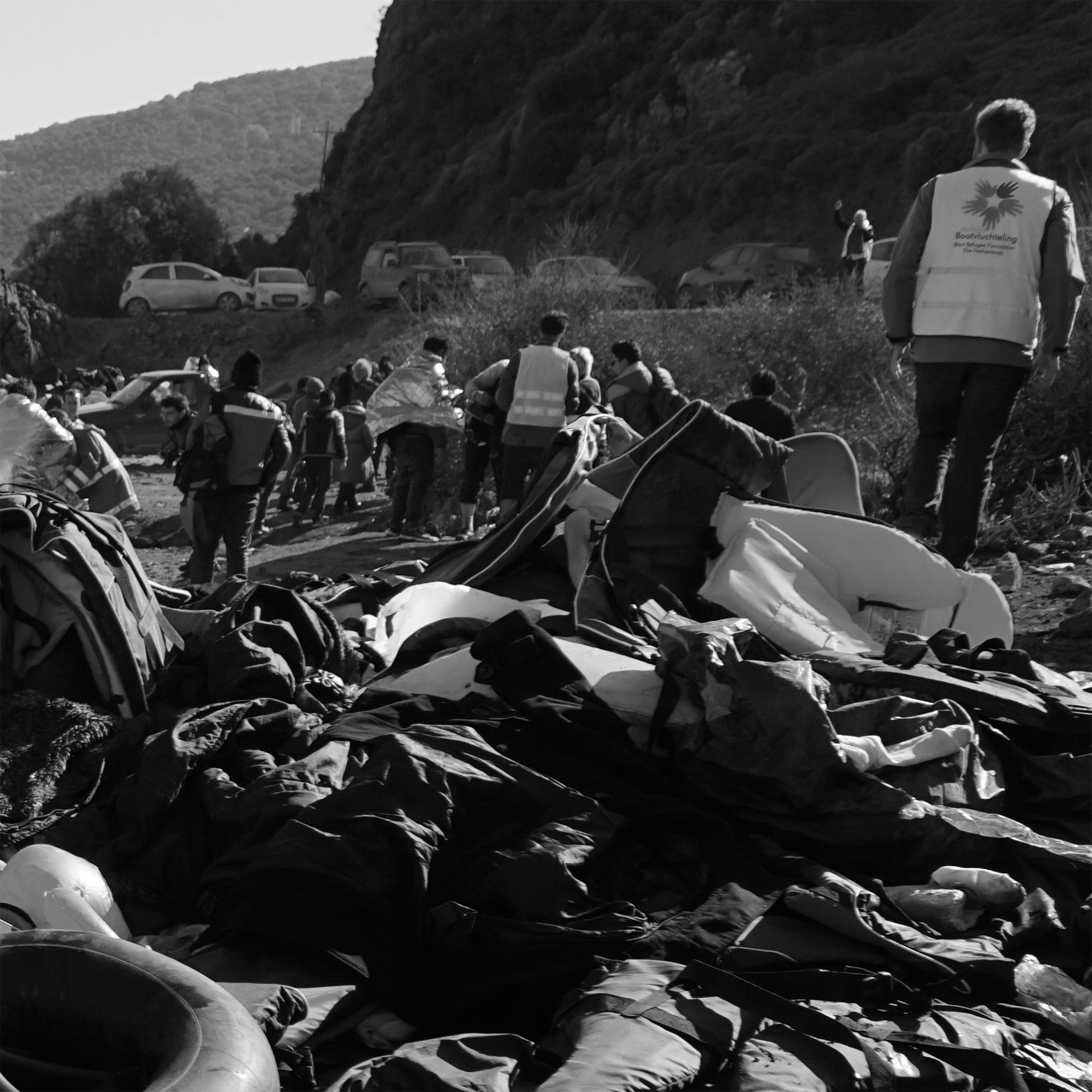 Schwarz-Weiß-Fotografie eines Strandes mit zahlreichen Rettungswesten und -reifen